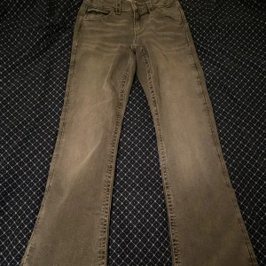 Grå jeans från Gina Tricot, bootcut - Snygga grå jeans i midwaist från Gina Tricot i storlek 164. Modellen har bootcut-ben med blå detaljer på bakfickorna. 