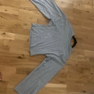 Grå långärmad basic tröja - En enkel och stilren grå långärmad tröja i mjukt material. Perfekt för lager-på-lager och funkar till det mesta. Tröjan har rund halsringning och rak passform.