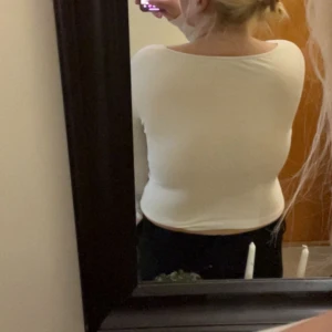 Vit croppad långärmad topp med knappar - Säljer en vit croppad långärmad topp i ribbad bomull med knappdetaljer framtill och v-ringad hals. Perfekt till jeans eller kjol för en enkel och snygg look.