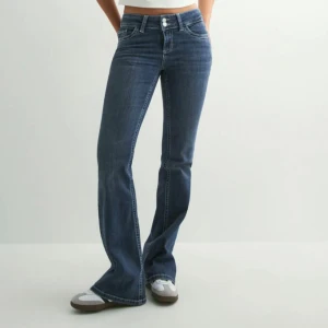 Blå bootcut jeans med broderade fickor - Snygga blå bootcut jeans med coola broderade detaljer på bakfickorna. Jeansen har hög midja, klassisk femficksdesign och är gjorda i stretchigt denim för skön passform. Perfekta för dig som vill ha en trendig och avslappnad look.