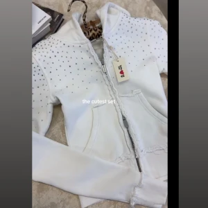 Vit hoodie med strass från Hidden Cult - Supersnygg vit hoodie från Hidden Cult med strassdetaljer över hela tröjan och logga i strass på ryggen. Tröjan har huva, dragkedja framtill och två fickor. Perfekt för dig som gillar bling och vill sticka ut lite extra. Säljer den då jag tog för liten storlek så den e endast testad! Ny pris ca 1300kr säljer för 999kr (kommer inte sänka priset mer då man redan får 300kr billigare)🤍