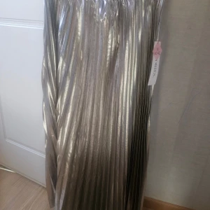 Plisserad silverkjol från & Other Stories - Säljer en plisserad långkjol i metallic silver från & Other Stories. Kjolen har ett glansigt tyg och resår i midjan för extra komfort. Perfekt statement-plagg med snyggt fall och cool futuristisk vibe.