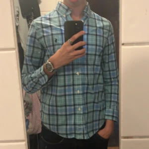 Rutig blå skjorta från Ralph Lauren - Snygg rutig skjorta från Ralph Lauren i olika blå nyanser med klassisk button-down krage och broderad logga på bröstet. Den passar dig som har xs bra och den är i fint skick, tveka inte att höras av vid intresse😊