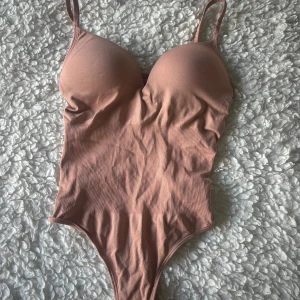 Rosa body  från H&M XS - Supersnygg rosa body från H&M i storlek XS. Den har vadderade kupor, smala axelband och en figurnära passform. Materialet är mjukt och stretchigt!