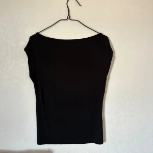 Svart ärmlös topp från 157 - En stilren svart ärmlös topp från 157 med enkel design och rund halsringning. Toppen är figurnära och passar perfekt till jeans eller kjol. Tillverkad i mjukt material som känns skönt mot huden.