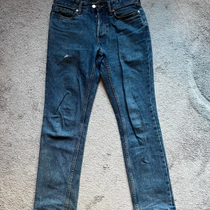 Blå jeansbyxor från Cubus 29/32 - Snygga blå jeansbyxor från C Denim i modellen Regular Rigid. Klassisk femficksdesign med raka ben och normal passform. Jeansen har en mörkblå tvätt och är tillverkade i slitstarkt jeanstyg. Perfekta för dig som gillar enkel och tidlös stil. Skriv för mer bilder