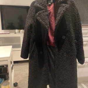 Svart teddyjacka från Anine Bing - Säljer en lång, svart teddyjacka från Anine Bing med stora slag och knappar framtill. Jackan har en oversized passform och är tillverkad i mjukt teddy-material som ger en riktigt mysig vibe. Perfekt för kalla dagar när du vill vara både varm och snygg.