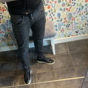 Replay Anbass svarta slim jeans - Säljer ett par svarta Replay Anbass jeans i slim fit. Jeansen har klassisk femficksdesign, snygga detaljer och en mörk tvättad look. Perfekta för dig som gillar en smalare passform och vill ha ett par stilrena jeans i garderoben.