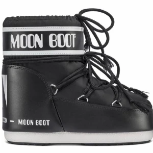 Svarta Moon Boots med snörning - Moon Boot i svart med vit logga och snörning runt hela skaftet. Skorna har en rund tå, platt sula. Perfekta för vintern med sin ikoniska design och vadderade känsla. Tjock sula och högt skaft ger extra värme och stil. Knappt använda❤️