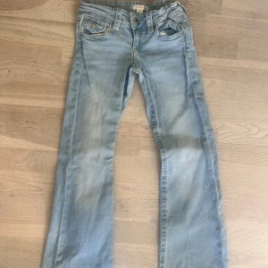 Ljusblå barn jeans från Gina Tricot! - Säljer ett par ljusblå jeans från Gina Tricot med klassisk femficksdesign och snygga detaljer på bakfickorna. Jeansen har raka ben och normal passform, perfekt till vardagslooken. Materialet är mjukt denim i bomull med en skön känsla.
