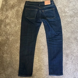 Mörkblå jeans från Acne Studios 27/32 - Snygga mörkblå jeans från Acne Studios i klassisk femficksmodell. Jeansen har raka ben, normal passform och är tillverkade i bomull med en liten del elastan för extra komfort. Perfekta för dig som gillar stilrena och tidlösa jeans.