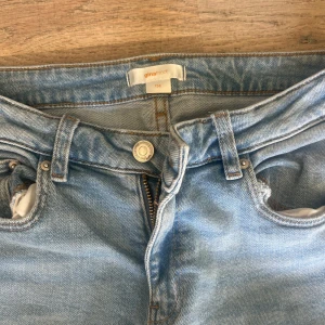 Ljusblå bootcut jeans från Gina Tricot - Snygga ljusblå jeans från Gina Tricot i klassisk bootcut-modell. Jeansen har fem fickor, bälteshällor och dragkedja med knapp. Tillverkade i mjukt bomullsjeans-tyg.