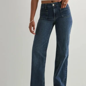 Mörkblå wide jeans med fickor - Snygga mörkblå jeans med raka, vida ben och stora framfickor.  Mid waist  midja och klassisk femficksdesign baktill. Jeansen är tillverkade i ett robust denimtyg som ger en cool och avslappnad look. Aldrig använda med prislapp kvar och säljer då dom va för långa på mig 💗