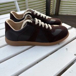 Maison Margiela Gats - Riktigt snygga maison margiela gats I färgen brun, med creme vita skosnören. Dem är knappast använda och redo för en ny ägare. Hör av er vid funderingar