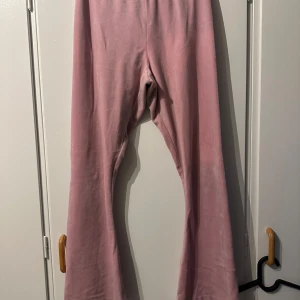 Rosa velourbyxor Juicy Couture XS - Mysiga rosa velourbyxor från Juicy Couture med bootcut och strassdetaljer. Juicy-logga i strass på baksidan och liten J framtill. Perfekta för en chill och trendig look. Lite uppsydda nere vid benen så de passar för den som är 153, men det går att sprätta upp så blir de som vanligt