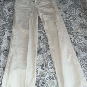 Vita raka byxor i bomull - Snygga vita byxor med rak passform och klassisk look. Tillverkade i bomull för en skön känsla och stilren finish. Perfekta att matcha med en enkel t-shirt eller hoodie. Byxorna har normal midja och är utan synliga detaljer eller mönster.