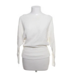 Vit ribbad stickad tröja - Säljer en vit stickad tröja med ribbad struktur och bred mudd i midjan. Tröjan har lång ärm och en avslappnad, loose passform som ger en chill vibe. Perfekt att styla med jeans eller kjol för en enkel men snygg look.