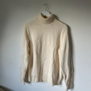 Beige polotröja i ull från Arket - Säljer en stilren beige polotröja från Arket i mjuk ull. Tröjan har ribbade muddar och hög polokrage, perfekt för lager-på-lager. Enkel och clean design som funkar till allt. Superskön och varm för kyliga dagar. 3O1