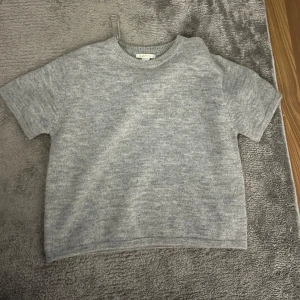 Grå stickad kortärmad tröja Gina Tricot - Mysig grå stickad tröja från Gina Tricot med korta ärmar och rund halsringning. Aldrig använd, endast testad!!