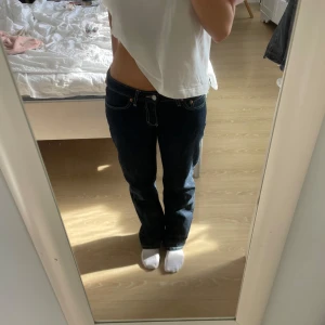 Weekday jeans - Säljer ett par mörkblå jeans med låg midja och raka ben. Klassisk femficksmodell med kontrastsömmar och knappgylf. Perfekta för dig som gillar en avslappnad och tidlös look.
