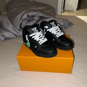 Louis Vuitton svartvita sneakers - Exklusiva Louis Vuitton sneakers i svart och vitt med tydlig LV-logga på plösen och sidan. Skorna har vita snören, svart sula och detaljer i skinn. Kommer med originalkartong, extra skosnören, dustbags och äkthetsbevis från StockX.