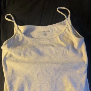 Ljusgrå linnetopp från Brandy Melville - Enkel och stilren ljusgrå linnetopp från Brandy Melville. Toppen har smala axelband och är tillverkad i mjuk bomull, perfekt för en avslappnad look. Passformen är normal och toppen är ärmlös, vilket gör den lätt att matcha med olika outfits. Använt men fint skick, sitter loose på mig som har breda axlar och strl S!