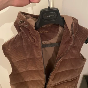 Stenströmsväst - Snygg brun dunväst i manchester från stenströms. Perfekt till höst eller vår. Storlek M. Den har en liten defekt längst ned där bak som ni ser på sista bilden men det är inget man märker