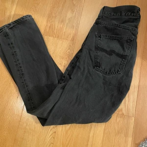 Svarta jeans från Nudie Jeans - Säljer ett par svarta jeans från Nudie Jeans då de ej passar mig länge. W31 L32. Svarta sömmar på bakfickorna och diskret logga. Slim/straight passform.