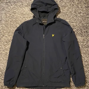 Lyle & Scott vindjcka - Väldigt snygg och skön marinblå vindjacka, lätt i materialet. Jackan är i toppen skick utan några som helst defekter eller fläckar. Åtdragbar vid midjan och luvan. Nypris ligger runt 1000kr. Storlek S. Hör av dig vid frågor eller funderingar! Pris kan diskuteras :) 