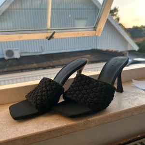 Svarta klackade sandaler från Primark - Svarta sandaler från Primark med fyrkantig tå och medel/låg klack. Ovandelen är i grovstickad syntet som ger en cool textur. Perfekta för dig som gillar trendiga och stilrena skor med en twist. Säljes i storlek 37. Aldrig använda, med prislapp kvar.