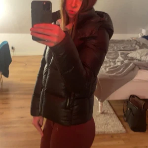 Svart pufferjacka Calvin Klein - Säljer en svart pufferjacka från Calvin Klein med huva och dragkedja. Jackan är köpt på Plick, har en liten sminkfläck (3bilden) som säkert kan få bort med en till tvätt. Trycket på bröstet och armen är borttvättat tyvärr. Jackan är i storlek s men passar xs oxå. 