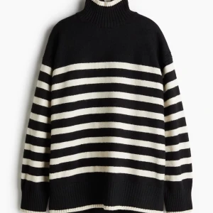 Randig svartvit polotröja - Snygg svart och vit randig polotröja med hög krage och breda ribbade muddar. Oversized fit och stickad i mjukt material, perfekt för kyliga dagar. Klassisk look som funkar till allt och ger en cool vibe.