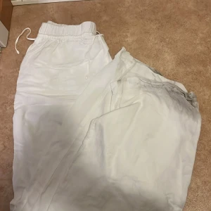 Vita linnebyxor från H&M - Säljer ett par fräscha vita linnebyxor från H&M. Byxorna har resår och snörning i midjan för skön passform. Perfekta för varma dagar och chill vibes. Tillverkade i en linnemix som känns lätt och luftig.