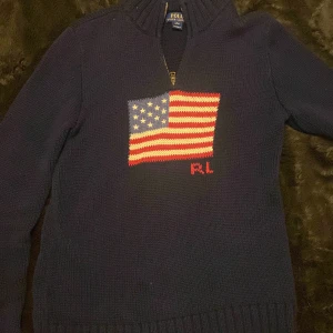 Mörkblå stickad tröja Polo Ralph Lauren - Mörkblå stickad tröja från Polo Ralph Lauren med halv dragkedja och amerikansk flagga broderad på bröstet. RL-broderi i rött under flaggan. Tröjan har hög krage och är perfekt för kyligare dagar. Den är helt ny inte ens använd barat provat köpte för 3567 och säljer för 1000 mkt bra pris såklart äkta bilderna blev lite dålig ljuset och så den har inte lite smuts enes sällsynt model riktigt snygg perfekt för dig som vil sticka ut 💸