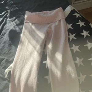 Ljusrosa mjukisbyxor från Gina Tricot - Supermysiga ljusrosa mjukisbyxor från Gina Tricot med bred ribbad midja. Byxorna är stickade och har en relaxed fit, perfekta för chill dagar hemma. Materialet är mjukt och stretchigt för extra komfort.