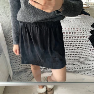 Svart kjol med resår - Enkel svart kortkjol i mjuk med stretchig resår i midjan. Kjolen har en avslappnad passform och är lite längre i modellen men går att vika ner. Storlek S men passar de flesta. 