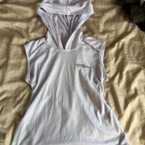 Ljuslila ärmlös hoodie från Pro-Sport - Ljuslila ärmlös topp från Pro-Sport med huva och lila sömmar. Sportig look med tryckt logga på bröstet (märket har gått upp lite vid kanten). Suuuperskönt material!! Märkt i storlek L men den ska va tajt i modellen så den är mer som S