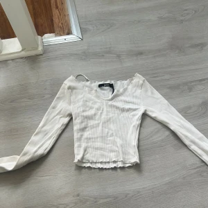 Vit ribbad långärmad topp Bik Bok - Säljer en vit ribbad långärmad topp från Bik Bok i storlek S. Toppen har v-ringning, croppad passform och vågig kant vid hals och nederdel. Perfekt att styla med jeans eller kjol för en fräsch look. Har kanske använt två gånger😊förlåt för den va så skrinklig