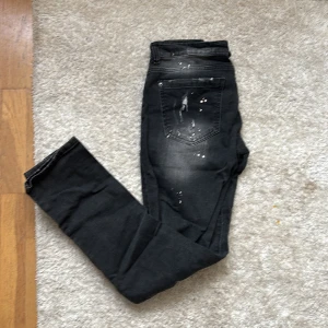 Dsquared jeans - Svarta jeans med skinny fit och coola slitningar på benen samt vita färgstänk för en edgy look. Jeansen har klassisk femficksdesign och dragkedja. Perfekta för dig som gillar streetstyle och vill sticka ut.