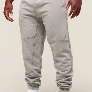 Power joggers från Gymshark - Säljer mina Gymshark Heritage-byxor. En modell inspirerad av “Golden Era” bodybuilding med lite tyngre och snyggare look.  • Premiumtvättat tyg • Ribbad panel i grenen för bättre rörlighet • Justerbar midja med dragsko  Passform: Oversized (lite lösare stil) Storlek: M Modellen är 175 cm och bär M – passar även om du är runt den längden, men oversized så finns det lite spelrum) , Byxorna är i okej skick, finns lite tecken på användning. Nypris: 599kr