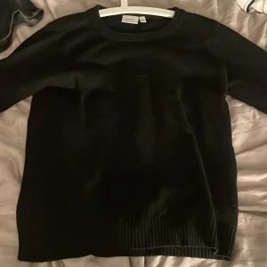 Svart stickad tröja från Vila - En klassisk svart stickad tröja från Vila med rund halsringning och långa ärmar. Tröjan har ribbade muddar vid ärmslut och nederkant, vilket ger en snygg och enkel look. Perfekt för lager-på-lager under kyliga dagar. Även väldig skön tröja!💞