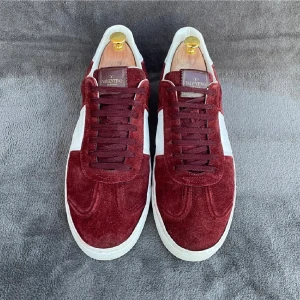 Valentino Garavani vinröda sneakers mocka - Snygga sneakers från Valentino Garavani i vinröd mocka med vita detaljer och vit sula. Klassisk låg modell med snörning och rund tå. Ikoniska nitar baktill på sulan ger extra edge. Perfekta för dig som vill sticka ut med stilrena och lyxiga skor.