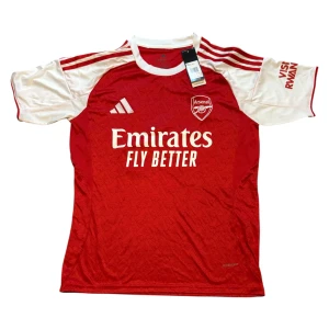 Arsenal hemmatröja Adidas röd/vit - Säljer en officiell Arsenal hemmatröja från Adidas med Gyökeres 14 på ryggen. Tröjan är röd med vita ärmar, har broderat klubbmärke och Adidas-logga samt tryckta sponsordetaljer. Tillverkad i lätt och ventilerande AEROREADY-material, perfekt för match eller träning.