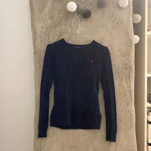Ralph lauren polo tröja - Mörkblå kabelstickad tröja från Ralph lauren polo. Köpt för ca 1200kr gissar jag. Rött märke på framsidan. Kan gå ner i pris vid snabb affär! ⚠️KATT FINNS I HEMMET⚠️