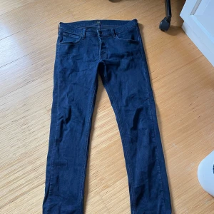 Mörkblå Lee Daren jeans W32 L32 - Snygga mörkblå jeans från Lee, modell Daren. Klassisk femficksdesign med Lee-logga på bakfickan och svart patch i midjan. Jeansen har rak passform och är tillverkade i mjukt denimtyg som sitter skönt hela dagen.