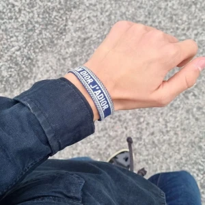 Blått Dor- armband - Armband i tyg, med broderad text på. Stilren och för din outfit samman. Fraktar samma dag inga konstigheter.