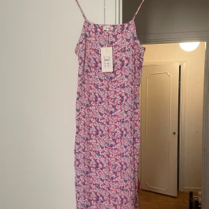Blommig långklänning från Levete Room (L) - Oanvänd supersöt långklänning från Levetē room. Reglerbara tunna axelband och sprund nertill på båda sidor. Blommigt mönster i rosa/flerfärgad. Storlek L ( upplevs mer som M) 100% viscose. Ny med tags. 