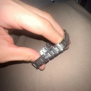 Silverfärgat armband från Lacoste - Snyggt armband i silverfärgad metall med rektangulära länkar och Lacoste-loggan ingraverad på flera av länkarna. Armbandet har en cool, modern design med texturerade detaljer som ger extra edge. Perfekt för dig som gillar stilrena accessoarer med lite attityd.