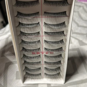 Svarta lösögonfransar i multipack - Säljer ett paket med flera par svarta lösögonfransar. Fransarna är långa, böjda och har en naturlig men markerad look. Perfekta för att ge extra volym och längd till dina egna fransar. Kommer i en vit ask med röd text.