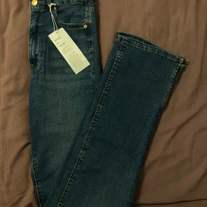 Gina tricot jeans  - Snygga blå jeans från gina tricot, modell Molly. Jeansen har guldfärgade detaljer och slits längst ner vid foten. Inte använt, prislappen finns kvar. 